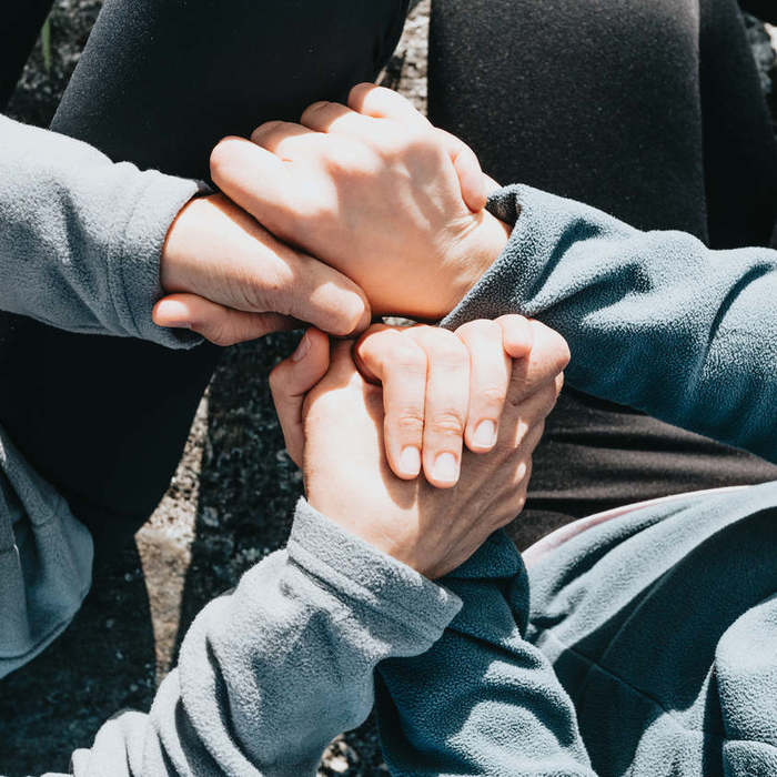 Large thumb looking down toward people holding hands and sitting