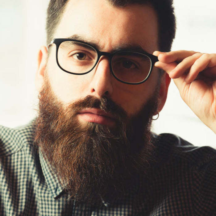 Large thumb man looks at the camera as he adjusts his glasses