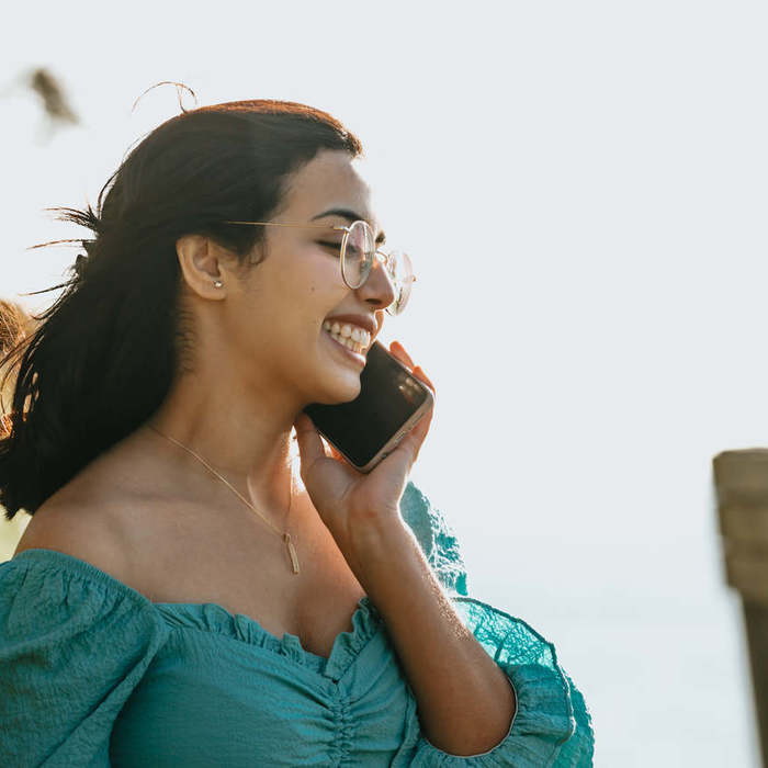 Large thumb woman smiles and holds a cellphone to her ear