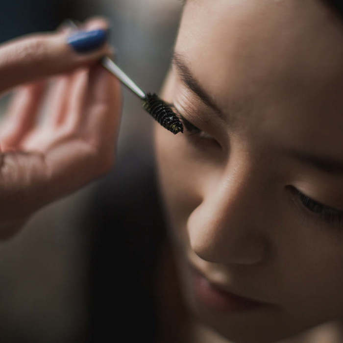 Large thumb woman getting mascara makeup