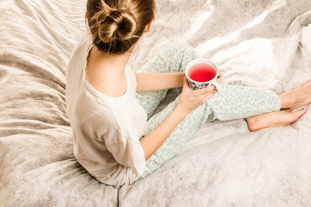 ベッドでお茶を飲む女性