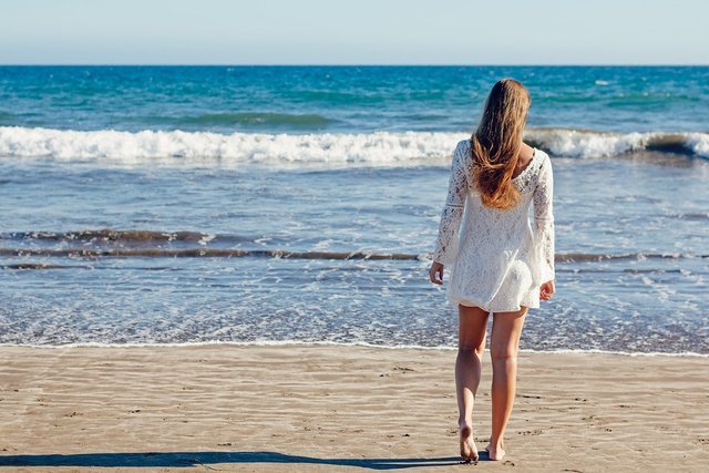 砂浜を歩く女性の後ろ姿