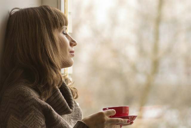 窓辺でコーヒーを飲む女性