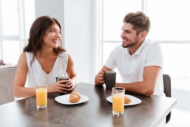 テーブルで朝食を食べる男女