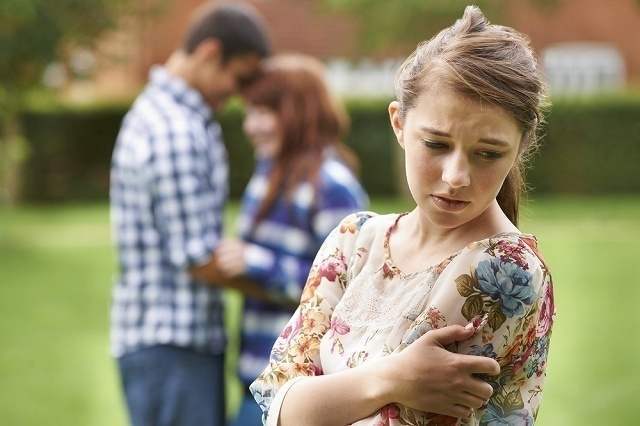 抱き合う男女を見て悲しむ女性