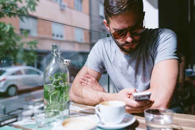 カフェで携帯を見つめる男性